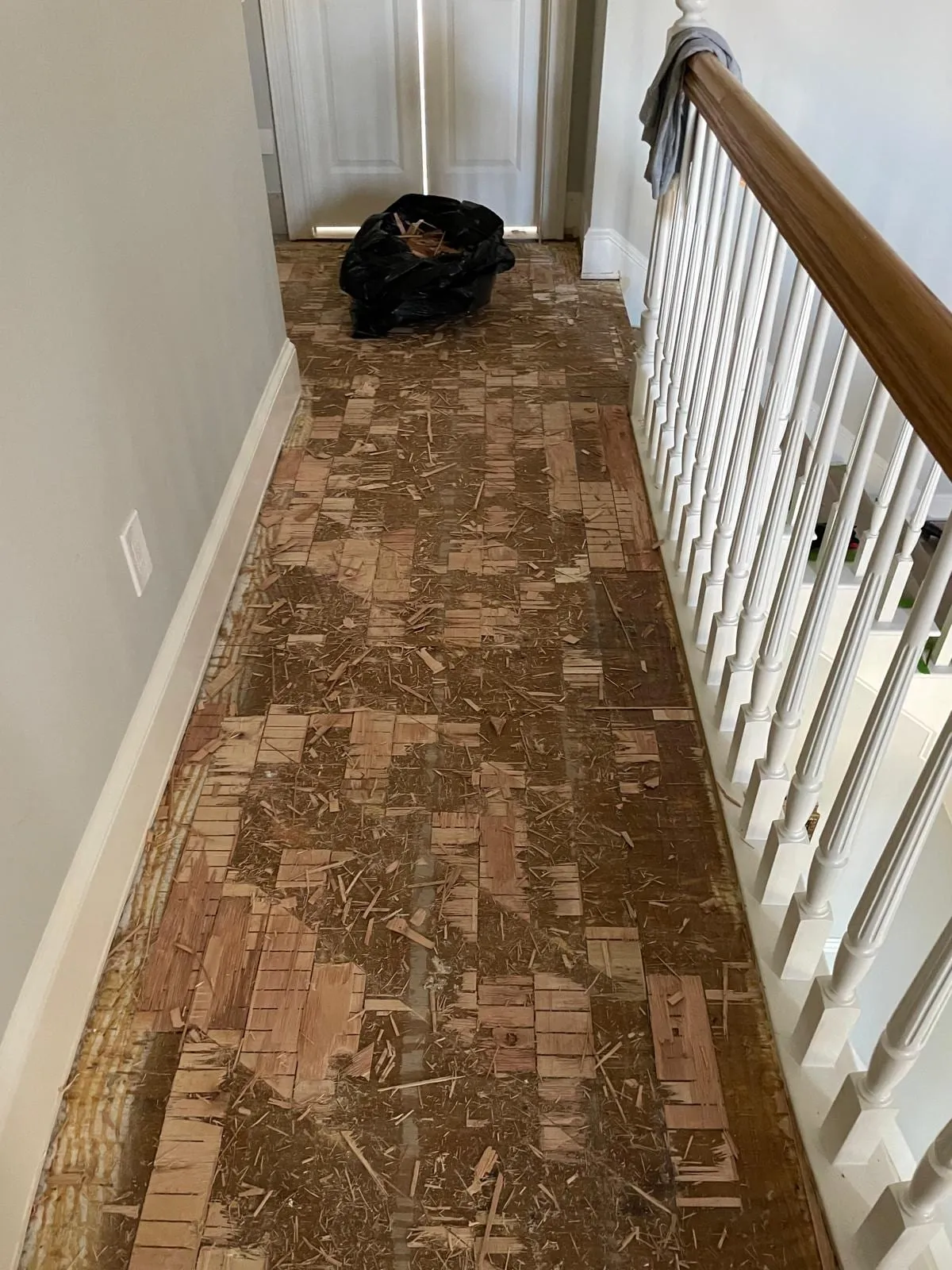 Worn parquet flooring in the hallway before replacement