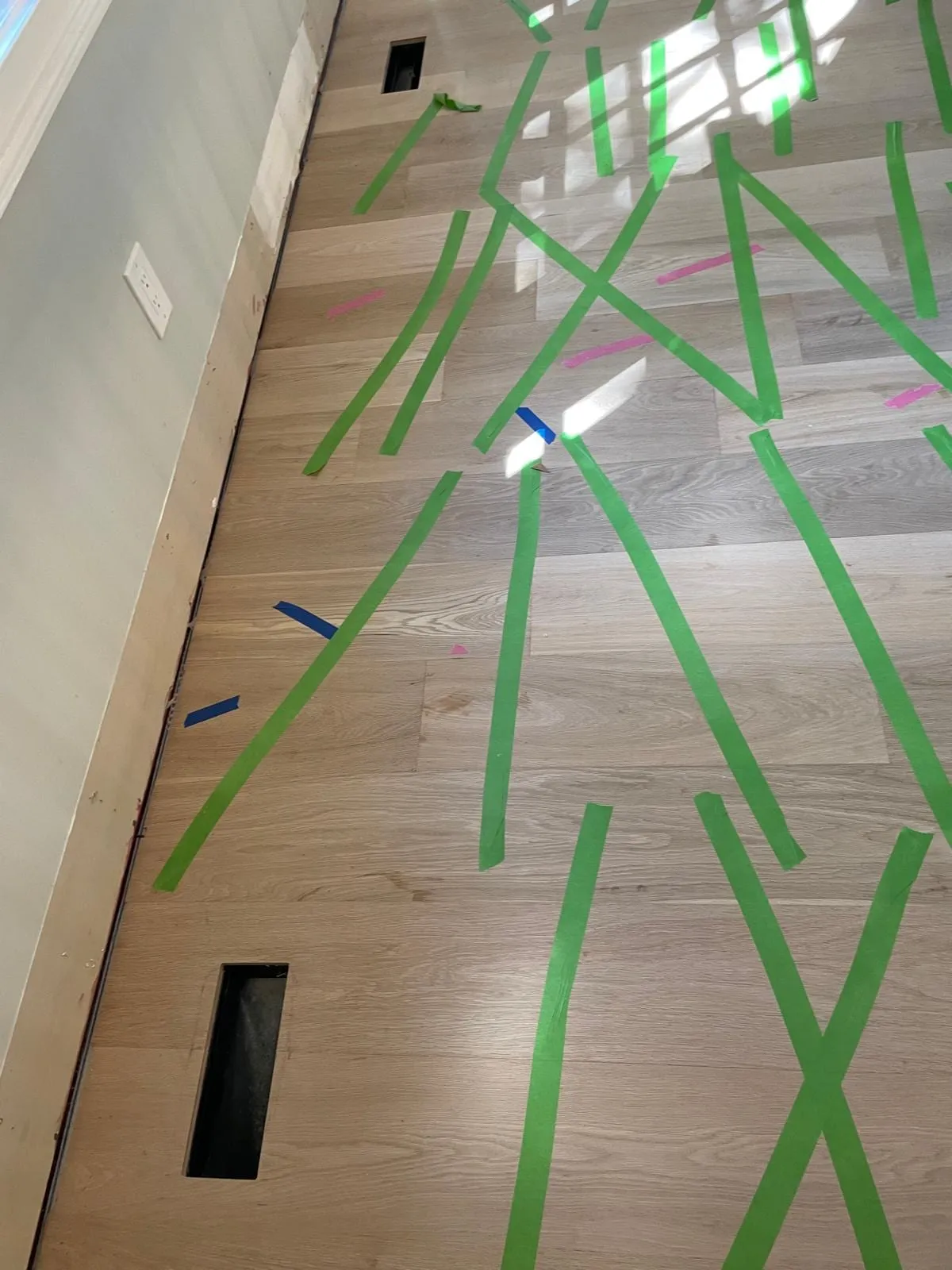 Hardwood planks being laid and held with painter’s tape during installation